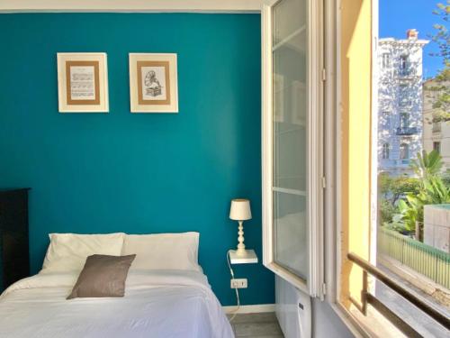 una camera da letto blu con un letto e una finestra di Budget studio Berlioz a Nizza