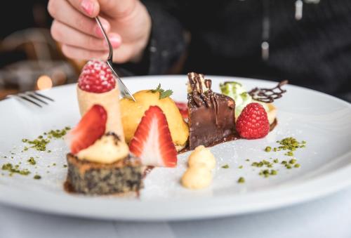 a person eating a plate of food with fruit at TRAUBE BRAZ Alpen Spa Golf Hotel in Bludenz