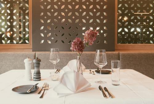 una mesa con un mantel blanco y un jarrón de flores en TRAUBE BRAZ Alpen Spa Golf Hotel en Bludenz