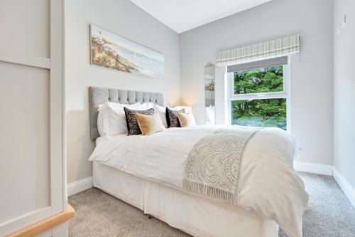 ein Schlafzimmer mit einem großen weißen Bett mit einem Fenster in der Unterkunft Quay House, North Coast 6 bedroom holiday home in Ballycastle