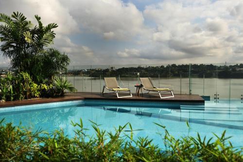 a swimming pool with two chairs and a table at Pullman Abidjan in Abidjan