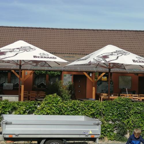 two white umbrellas in front of a restaurant at Privat Bohemia in Šatov
