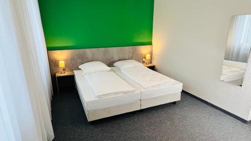 two beds in a room with a green wall at Creativ Park Hotel in Nuremberg