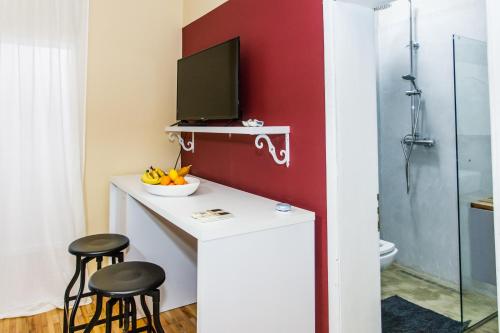 une salle de bains avec un comptoir avec deux tabourets et une télévision dans l'établissement Studio Apartments Villa 24, à Tirana