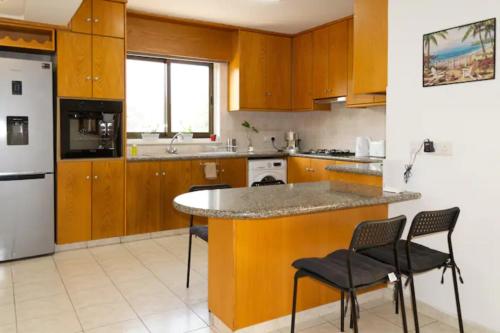 a kitchen with wooden cabinets and a counter with chairs at Guest Apartments in Limassol