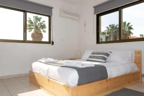 a bedroom with a wooden bed with two windows at Guest Apartments in Limassol