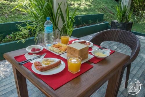 a table with a plate of breakfast food and orange juice at Simoya Nature Park in Dambulla