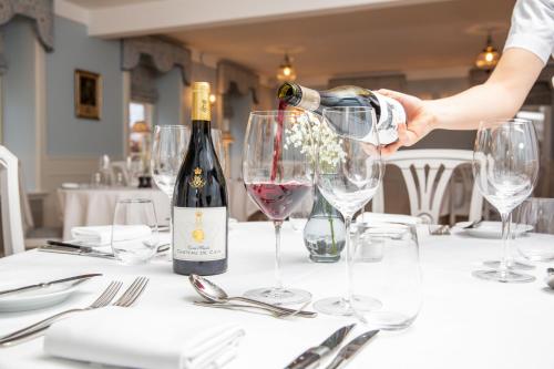 a person pouring a glass of wine on a table at Schackenborg Slotskro in Tønder