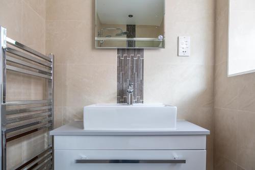 a bathroom with a white sink and a mirror at Stunning property fully refurbished in Birmingham