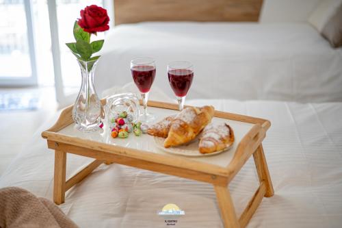 a table with two glasses of wine and croissants on a bed at IL CENTRO LUXURY SUITES in Bari