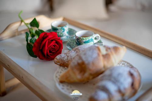 a table with croissants and cups of coffee and roses at IL CENTRO LUXURY SUITES in Bari