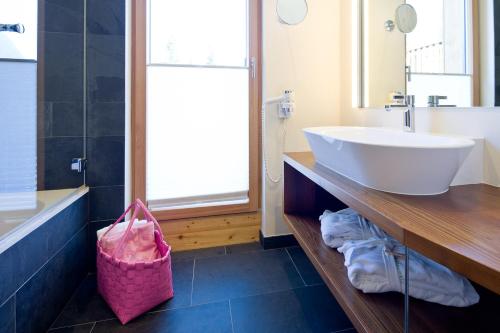 a bathroom with a sink and a tub and a mirror at TRAUBE BRAZ Alpen Spa Golf Hotel in Bludenz