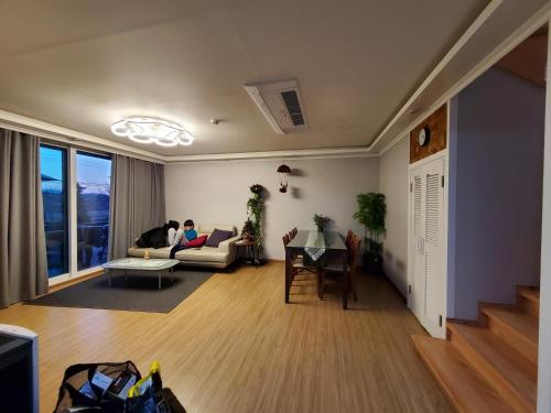 two people sitting on a couch in a living room at Grace River House-Block B in Hoengseong