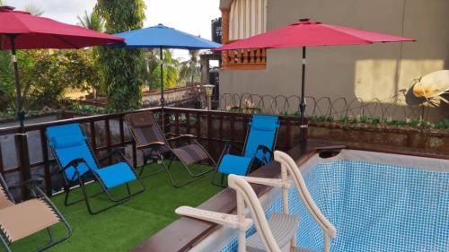 a group of chairs and umbrellas next to a swimming pool at PhaGibs Inn Hotel in Freetown