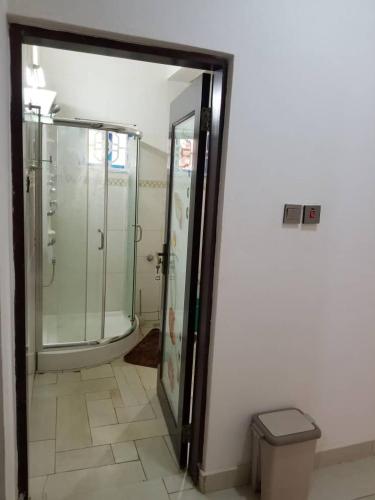 a bathroom with a glass shower and a trash can at PhaGibs Inn Hotel in Freetown