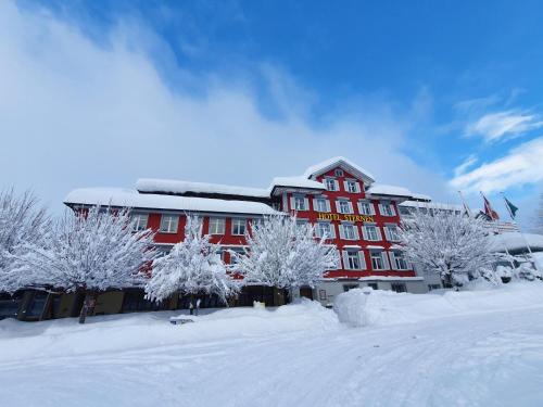 ein rotes Gebäude mit schneebedeckten Bäumen davor in der Unterkunft Hotel Sternen Unterwasser in Unterwasser