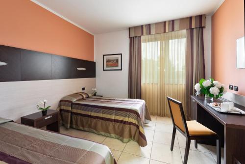 a hotel room with two beds and a desk at Record Hotel in Settimo Torinese