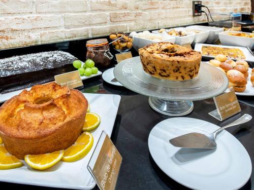 a table topped with cakes and other desserts on plates at Hotel Cassino Tower Campinas Cambuí By Nacional Inn in Campinas