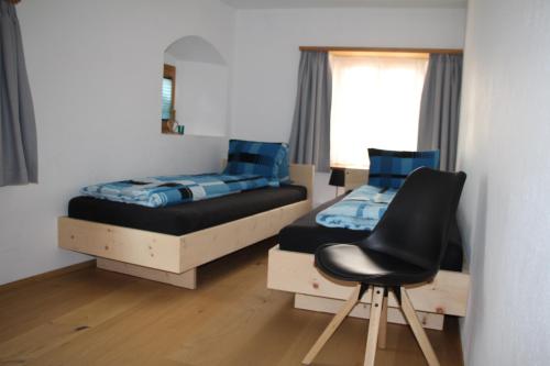a bedroom with two beds and a chair in it at Chasa Allegra Müstair in Müstair