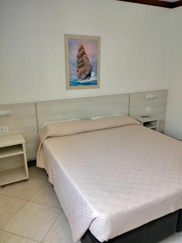 a bedroom with a bed and a picture on the wall at Pousada Solar Inn in Torres
