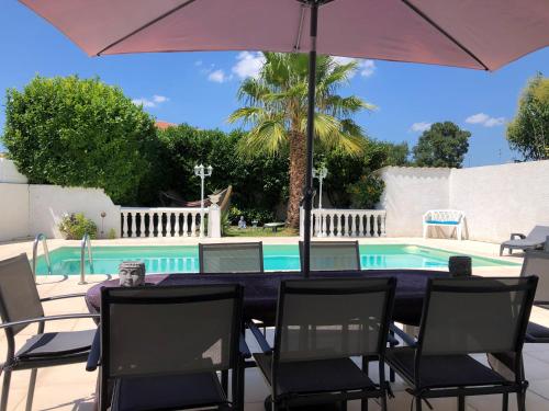 - une table avec des chaises et un parasol à côté de la piscine dans l'établissement Villa du sud ouest, à Béziers
