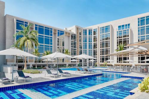 uma piscina com cadeiras e guarda-sóis em frente a um hotel em Hyatt Regency Cairo West em Cidade 6 de Outubro