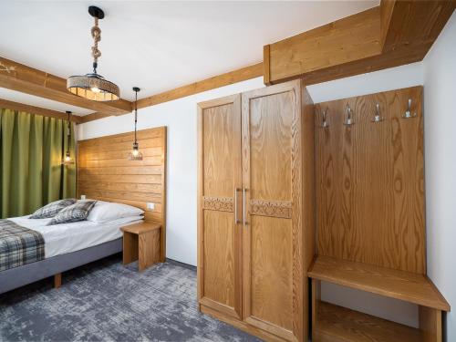 a bedroom with wooden cabinetry and a bed and a closet at Leśne Apartamenty in Białka Tatrzanska