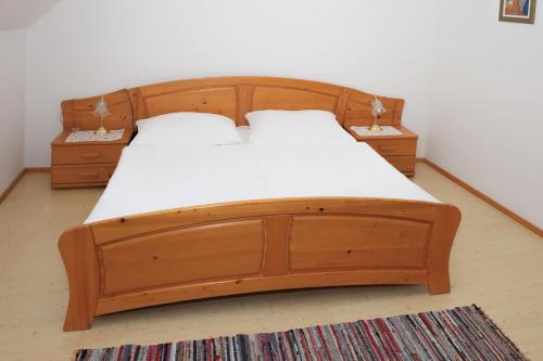 ein Holzbett mit weißer Bettwäsche und zwei Nachttischen in der Unterkunft Weinhof Gregor Raab in Unterretzbach