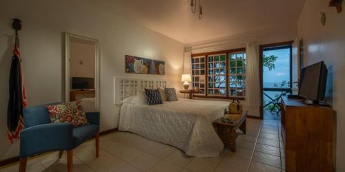 a bedroom with a bed and a tv and a chair at Pousada Enseada das Garças in São Pedro da Aldeia