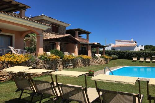 a yard with tables and a swimming pool in front of a house at Le Dimore di Nettuno in Olbia