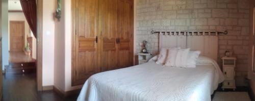 a bedroom with a white bed and a brick wall at El Cauce in San Medel