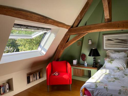 a bedroom with a red chair next to a bed at Villa Cassandre in Esvres