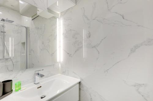 une salle de bain blanche avec un lavabo et un miroir dans l'établissement Charming apart -1BR-5P - République, à Paris
