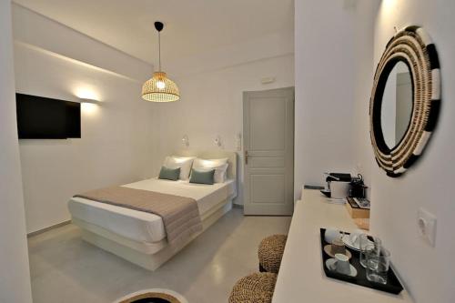 Habitación blanca con cama y espejo en Kleri's apartments 2 en Tinos Town