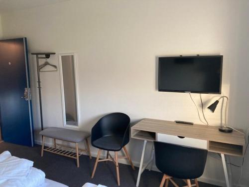 a room with a desk with two chairs and a television at Motel Trafikcenter Sæby in Sæby