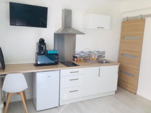 une cuisine avec des armoires blanches et une cuisinière dans l'établissement Studio 2 bien agencé et tout équipé, à Lorient