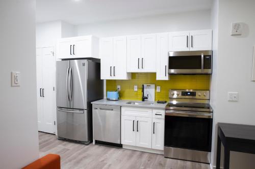a kitchen with white cabinets and a stainless steel refrigerator at Peachtree Suites - Jersey City in Jersey City