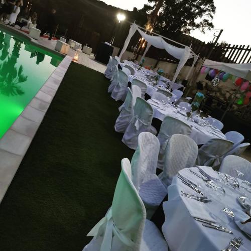 a group of white tables and chairs next to a pool at Imperial Park in Raffadali