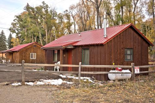 Cabaña de madera con techo rojo y valla en Four Seasons Lodge, en South Fork