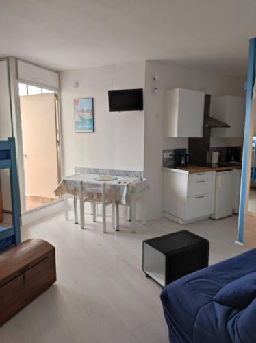 un salon avec une table et une cuisine dans l'établissement Agréable studio bord de mer, à Saint-Cyprien