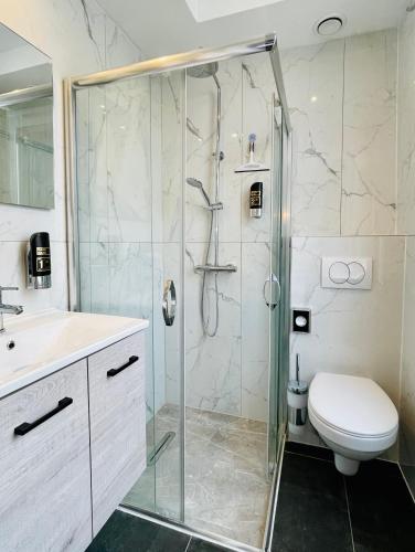 a bathroom with a shower and a toilet and a sink at City Apartments Grendelplein in Valkenburg