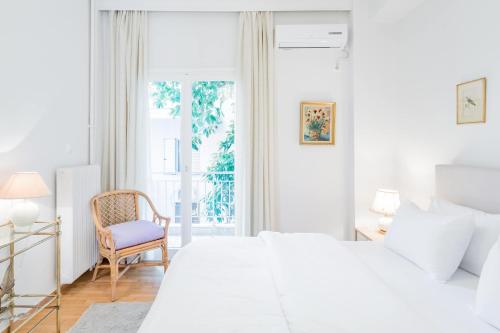 biała sypialnia z łóżkiem i krzesłem w obiekcie Koukaki Apartment with a Sunny Balcony, near the Acropolis w Atenach