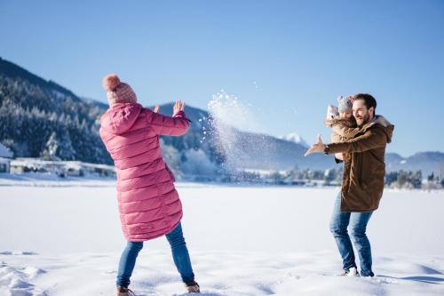 a man and a woman playing in the snow at Lakeside Petzen Glamping in Unterlibitsch