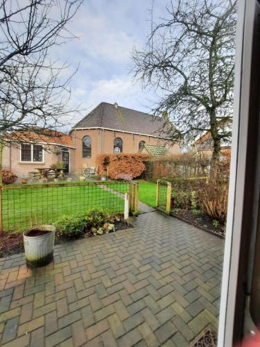 a house with a fence and a brick patio at 'It Mearke in Molkwerum