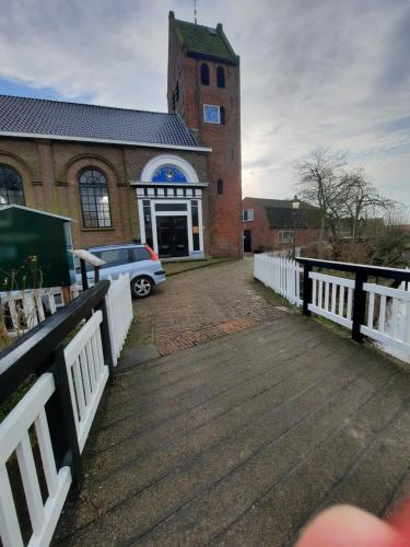 a church with a car parked in front of a building at 'It Mearke in Molkwerum