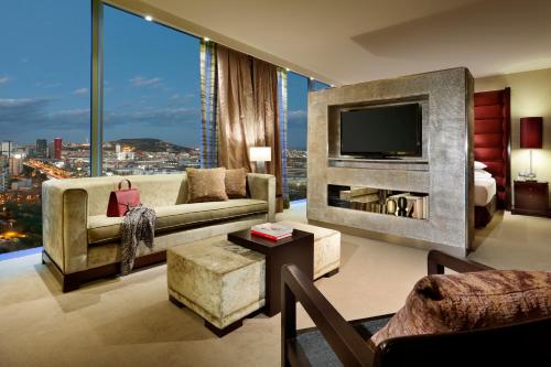 a living room with a tv and a large window at Hyatt Regency Barcelona Tower in Hospitalet de Llobregat