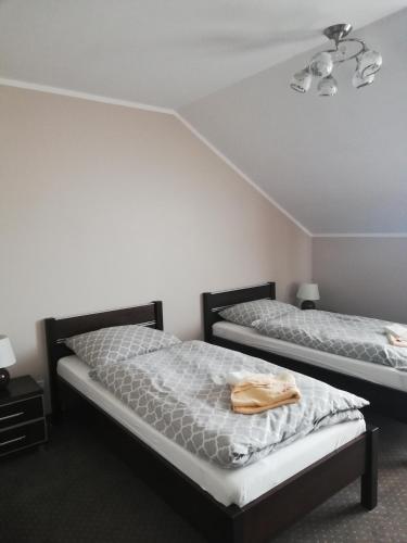 two beds in a room with white walls at Villa Dobry Adres in Dziemiany