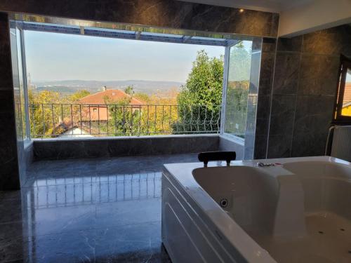 a bath tub in a bathroom with a large window at Butik Hotel Maşukiye in Masukiye