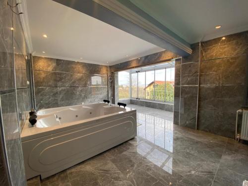 a large bathroom with a tub and a large window at Butik Hotel Maşukiye in Masukiye