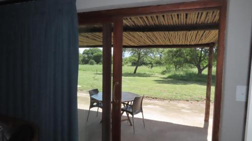 a table and a chair on a screened in porch at Sunset Lodge & Safaris in Guernsey Nature Reserve